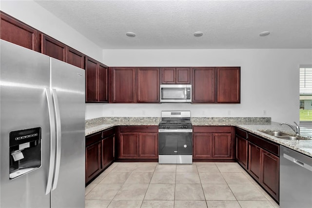 7223 SW 61st Pl, Ocala, FL 34474 - kitchen with appliances with stainless steel finishes, reddish brown cabinets, light stone countertops, a textured ceiling, and light tile patterned flooring