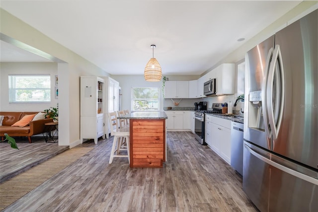 653 Goodwin Ave, New Smyrna Beach, FL 32169 - kitchen with appliances with stainless steel finishes, wood finished floors, a center island, a breakfast bar area, and white cabinets