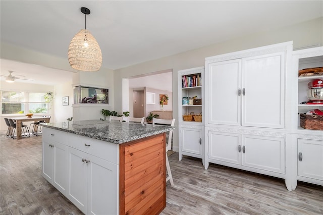 653 Goodwin Ave, New Smyrna Beach, FL 32169 - kitchen with light wood-style floors, white cabinets, a center island, and light stone counters