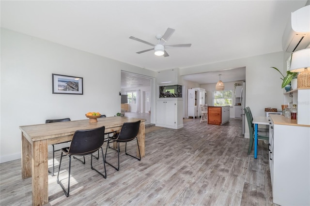 653 Goodwin Ave, New Smyrna Beach, FL 32169 - dining room featuring a wall unit AC, light wood-style floors, and a ceiling fan