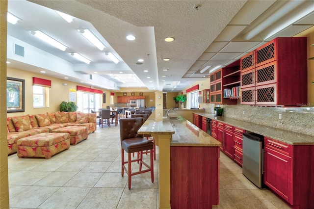 5300 S Atlantic Ave Unit 11302, New Smyrna Beach, FL 32169 - kitchen featuring dark brown cabinets, open floor plan, refrigerator, light tile patterned floors, and a kitchen breakfast bar