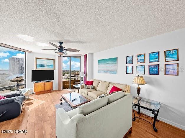 3023 S Atlantic Ave Unit 8010, Daytona Beach, FL 32118 - living room with a textured ceiling, ceiling fan, wood finished floors, baseboards, and expansive windows