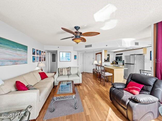 3023 S Atlantic Ave Unit 8010, Daytona Beach, FL 32118 - living area with a textured ceiling, light wood finished floors, and a ceiling fan