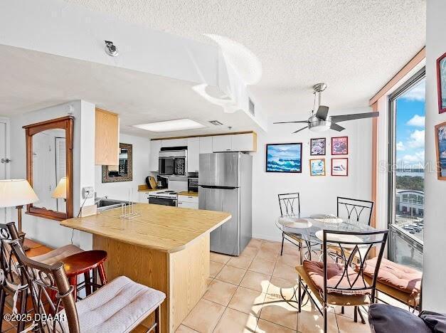 3023 S Atlantic Ave Unit 8010, Daytona Beach, FL 32118 - kitchen with appliances with stainless steel finishes, a peninsula, a textured ceiling, light countertops, and light tile patterned flooring