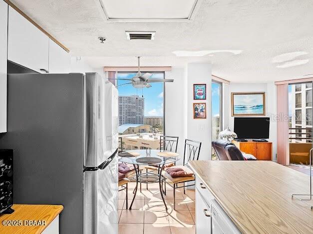 3023 S Atlantic Ave Unit 8010, Daytona Beach, FL 32118 - kitchen with freestanding refrigerator, white cabinets, light tile patterned floors, a ceiling fan, and open floor plan