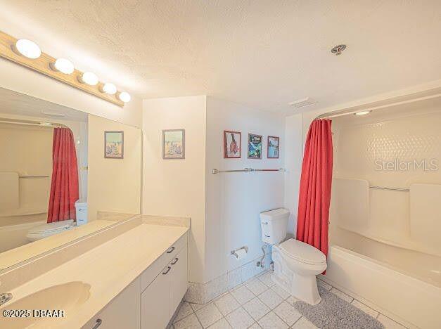 3023 S Atlantic Ave Unit 8010, Daytona Beach, FL 32118 - bathroom with toilet, shower / bath combo with shower curtain, vanity, tile patterned floors, and a textured ceiling