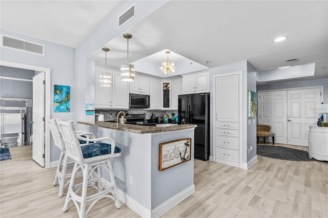 2 Oceans W Blvd Unit 608, Daytona Beach Shores, FL 32118 - kitchen with black appliances, light wood finished floors, white cabinetry, a peninsula, and decorative backsplash