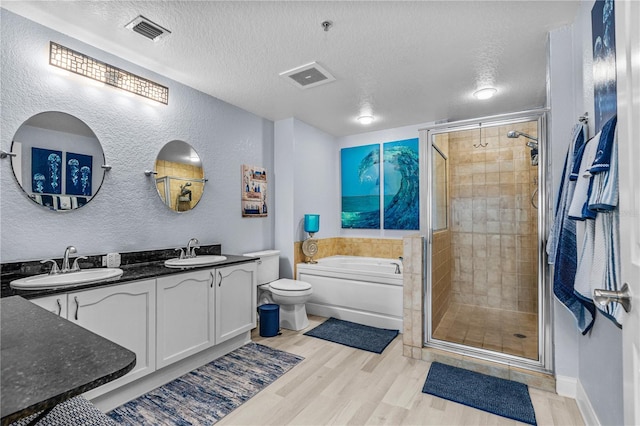 2 Oceans W Blvd Unit 608, Daytona Beach Shores, FL 32118 - full bathroom featuring a textured wall, a textured ceiling, a stall shower, double vanity, and wood finished floors