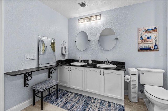 2 Oceans W Blvd Unit 608, Daytona Beach Shores, FL 32118 - full bathroom with wood finished floors, toilet, a textured wall, double vanity, and baseboards
