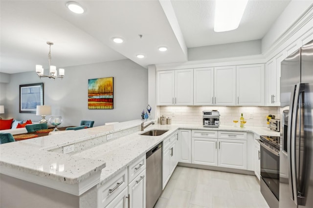 7 Riverwalk Dr Unit 305, New Smyrna Beach, FL 32169 - kitchen featuring appliances with stainless steel finishes, a sink, a peninsula, white cabinets, and backsplash