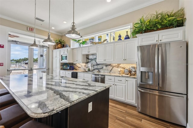 7 Riverwalk Dr Unit 305, New Smyrna Beach, FL 32169 - kitchen featuring appliances with stainless steel finishes, white cabinetry, a kitchen bar, tasteful backsplash, and ornamental molding