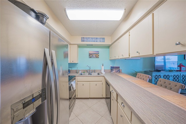 3615 S Atlantic Ave Unit 211, Daytona Beach, FL 32118 - kitchen with appliances with stainless steel finishes, a sink, a textured ceiling, light countertops, and light tile patterned flooring