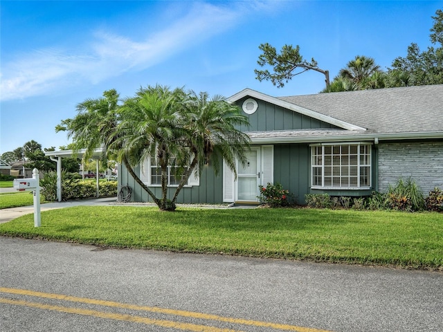 2 Birdie Dr, New Smyrna Beach, FL 32168 - view of front of home featuring board and batten siding, a front yard, and a shingled roof