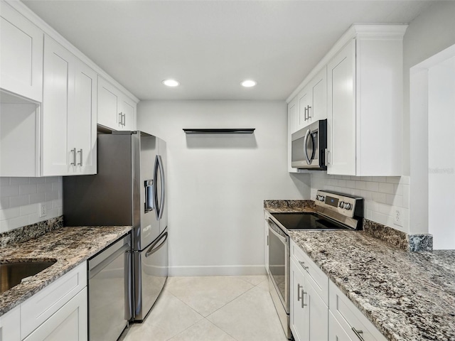2 Birdie Dr, New Smyrna Beach, FL 32168 - kitchen with appliances with stainless steel finishes, light tile patterned floors, stone counters, recessed lighting, and white cabinets