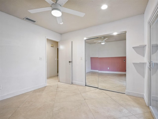 2 Birdie Dr, New Smyrna Beach, FL 32168 - unfurnished bedroom with a ceiling fan, light tile patterned floors, and a wainscoted wall
