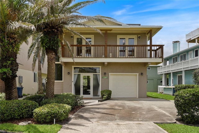 6956 Turtlemound Rd, New Smyrna Beach, FL 32169 - view of front facade with a balcony, driveway, stucco siding, an attached garage, and french doors