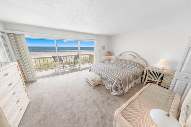 4777 S Atlantic Ave Unit B2, Port Orange, FL 32127 - bedroom with carpet, access to outside, view of water and beach, and a textured ceiling