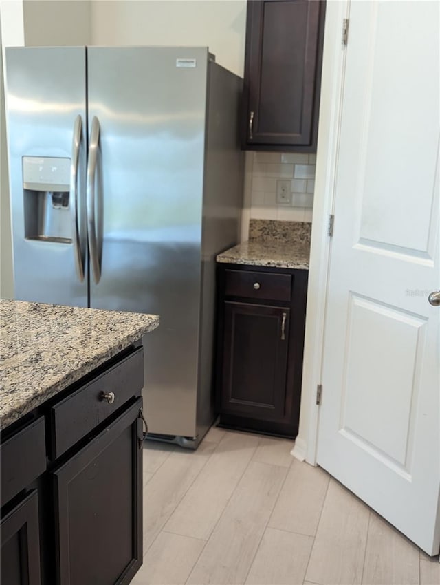 3103 Nova Scotia Way, New Smyrna Beach, FL 32168 - kitchen with stainless steel fridge, light stone countertops, decorative backsplash, and dark brown cabinetry