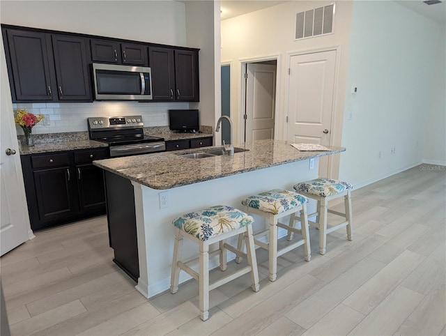 3103 Nova Scotia Way, New Smyrna Beach, FL 32168 - kitchen featuring stainless steel microwave, electric range oven, light wood-type flooring, a breakfast bar area, and light stone counters