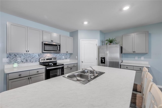 2731 Neverland Dr, New Smyrna Beach, FL 32168 - kitchen with stainless steel appliances, gray cabinets, decorative backsplash, light countertops, and recessed lighting