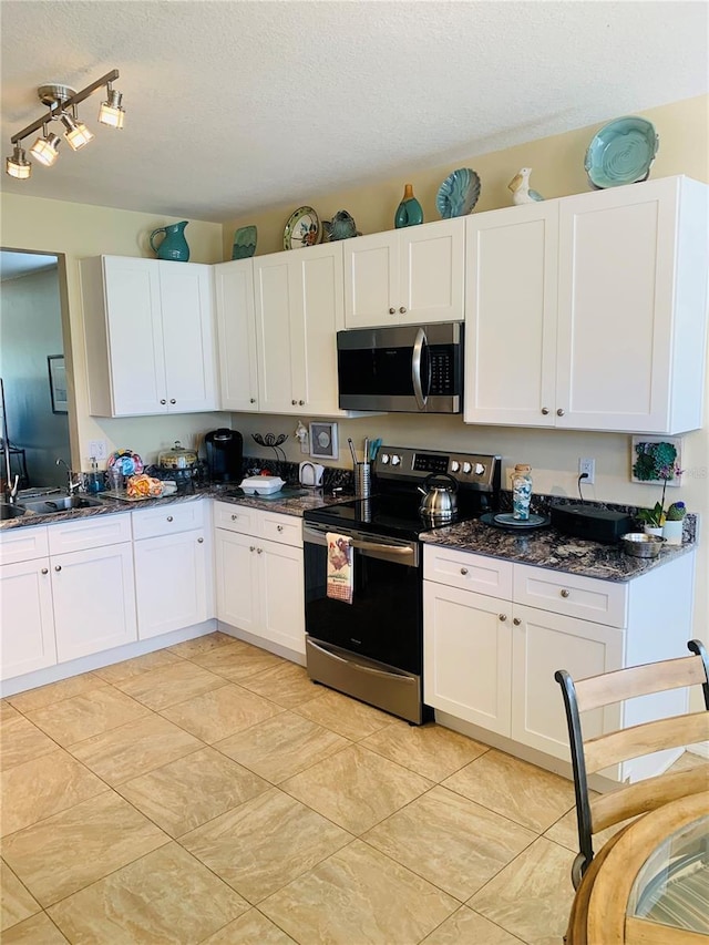 2672 Star Coral Ln, New Smyrna Beach, FL 32168 - kitchen featuring appliances with stainless steel finishes, a textured ceiling, white cabinetry, dark stone countertops, and light tile patterned floors
