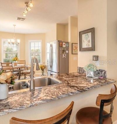 2672 Star Coral Ln, New Smyrna Beach, FL 32168 - kitchen featuring freestanding refrigerator, a breakfast bar, pendant lighting, and a chandelier
