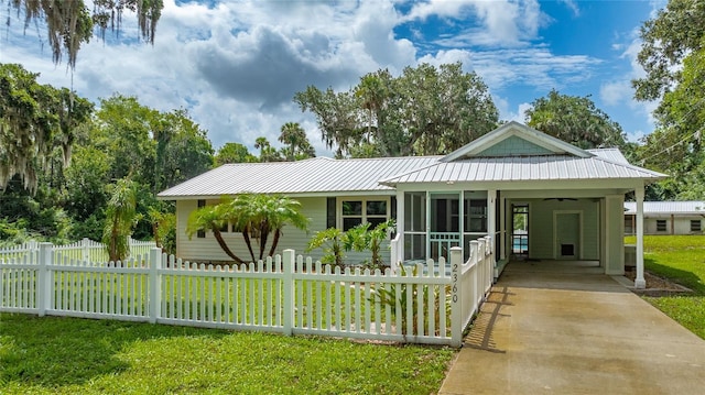 2360 Mooneyham Dr, New Smyrna Beach, FL 32168 - view of front of house with a fenced front yard, an attached carport, driveway, and a metal roof