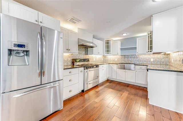 2360 Mooneyham Dr, New Smyrna Beach, FL 32168 - kitchen with stainless steel appliances, wall chimney exhaust hood, dark countertops, and light wood finished floors