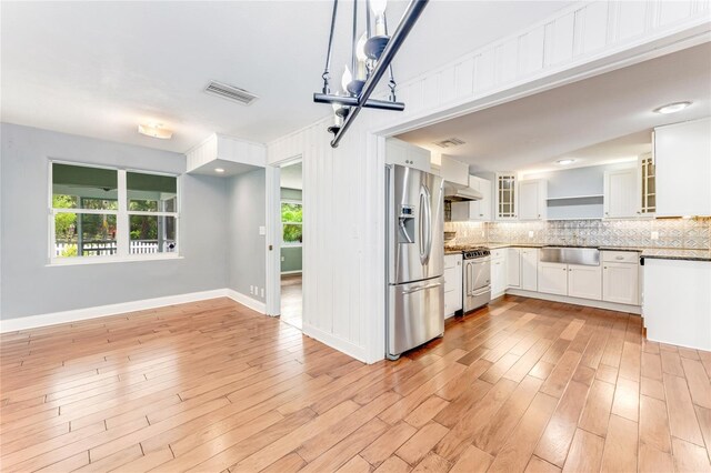 2360 Mooneyham Dr, New Smyrna Beach, FL 32168 - kitchen with stainless steel appliances, backsplash, exhaust hood, and light wood-style flooring