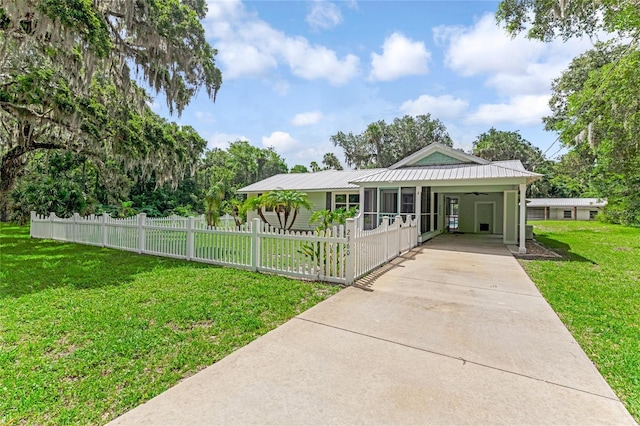 2360 Mooneyham Dr, New Smyrna Beach, FL 32168 - view of front of home with driveway, a fenced front yard, an attached carport, a metal roof, and a ceiling fan