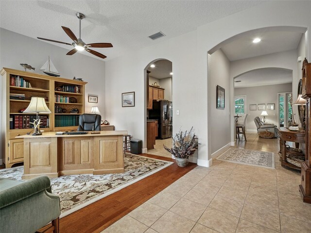 461 Luna Bella Ln, New Smyrna Beach, FL 32168 - home office featuring a ceiling fan, arched walkways, light tile patterned flooring, and a textured ceiling