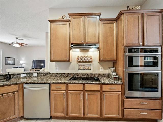 461 Luna Bella Ln, New Smyrna Beach, FL 32168 - kitchen with stainless steel appliances, under cabinet range hood, dark stone counters, ceiling fan, and a textured ceiling