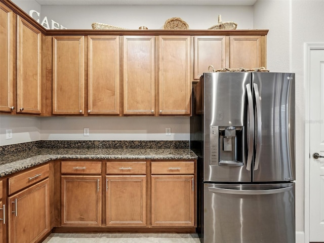 461 Luna Bella Ln, New Smyrna Beach, FL 32168 - kitchen with stainless steel fridge with ice dispenser, dark stone countertops, and brown cabinetry