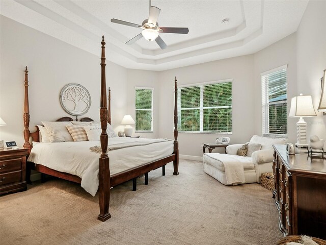 461 Luna Bella Ln, New Smyrna Beach, FL 32168 - bedroom featuring multiple windows, light colored carpet, a tray ceiling, and a ceiling fan
