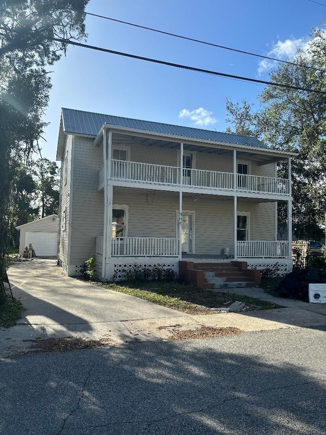 306 Murray St, New Smyrna Beach, FL 32168 - view of front of property featuring covered porch, a balcony, an outbuilding, and a metal roof