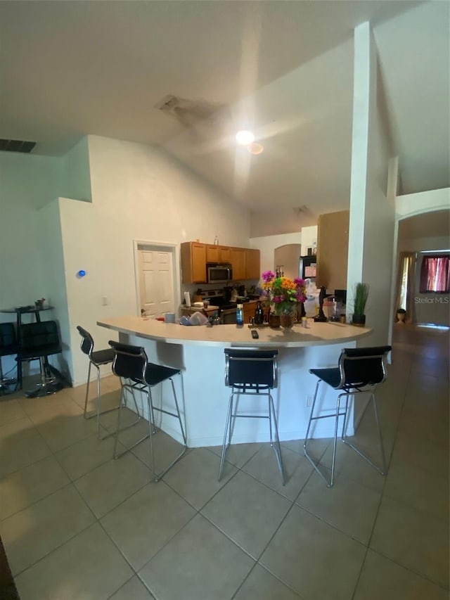 2122 Orange Tree Dr, Edgewater, FL 32141 - kitchen with stainless steel microwave, a breakfast bar area, light tile patterned flooring, and high vaulted ceiling