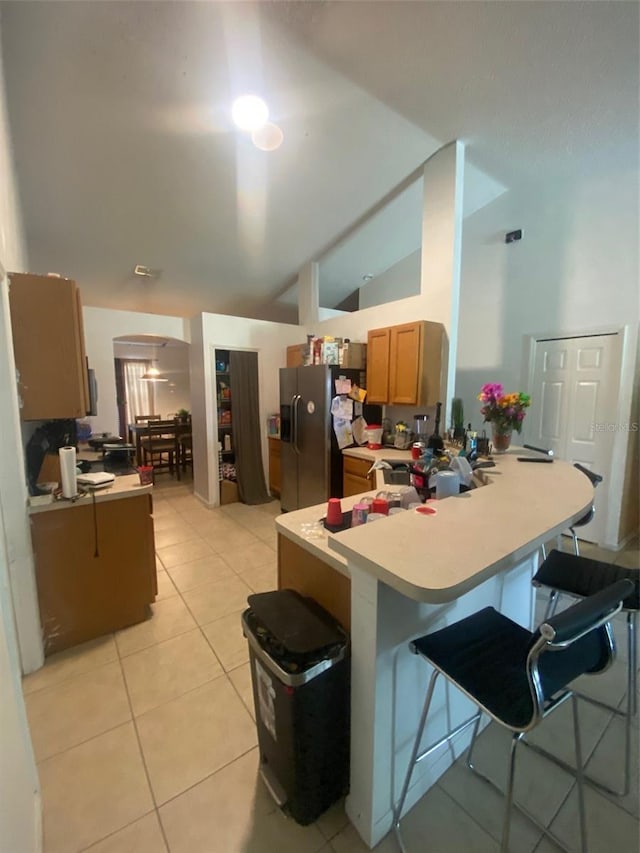 2122 Orange Tree Dr, Edgewater, FL 32141 - kitchen with stainless steel fridge, vaulted ceiling, a peninsula, light countertops, and light tile patterned floors