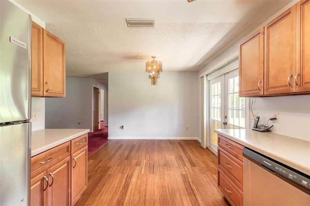 5060 Audubon Ave, De Leon Springs, FL 32130 - kitchen with appliances with stainless steel finishes, light countertops, light wood-type flooring, a textured ceiling, and a chandelier