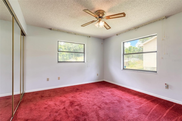 5060 Audubon Ave, De Leon Springs, FL 32130 - unfurnished bedroom with a textured ceiling, multiple windows, a closet, carpet floors, and a ceiling fan