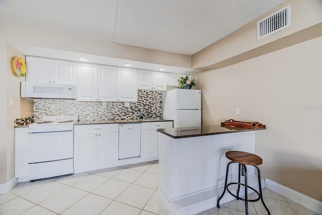3700 S Atlantic Ave Unit 108, New Smyrna Beach, FL 32169 - kitchen featuring white appliances, a textured ceiling, white cabinets, backsplash, and light tile patterned floors