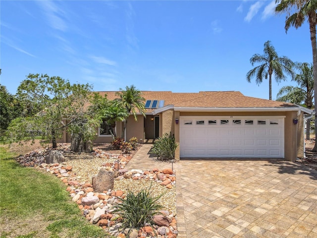 26 Creek Ct, Palm Coast, FL 32137 - view of front of house with an attached garage, roof mounted solar panels, stucco siding, and driveway