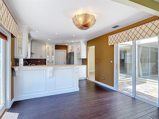 26 Creek Ct, Palm Coast, FL 32137 - kitchen featuring freestanding refrigerator, a peninsula, glass insert cabinets, white microwave, and dark wood-type flooring