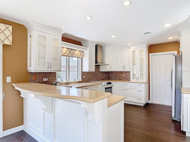 26 Creek Ct, Palm Coast, FL 32137 - kitchen featuring wall chimney range hood, electric range, a peninsula, freestanding refrigerator, and dark wood-style flooring