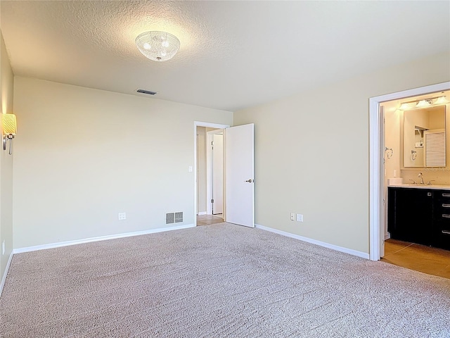 26 Creek Ct, Palm Coast, FL 32137 - unfurnished bedroom with light carpet, ensuite bath, a textured ceiling, and bar area