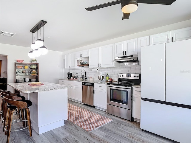 1421 Pine Tree Dr, Edgewater, FL 32132 - kitchen featuring stainless steel appliances, range hood, light wood-type flooring, white cabinets, and a ceiling fan
