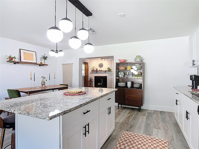 1421 Pine Tree Dr, Edgewater, FL 32132 - kitchen featuring light wood-type flooring, a kitchen bar, white cabinets, a kitchen island, and light stone countertops