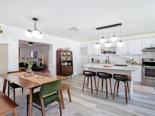 1421 Pine Tree Dr, Edgewater, FL 32132 - kitchen with stainless steel range with electric cooktop, under cabinet range hood, white cabinets, tasteful backsplash, and a center island