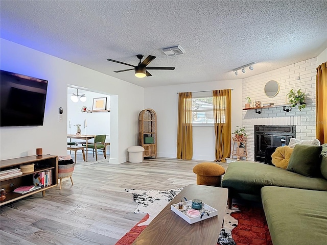 1421 Pine Tree Dr, Edgewater, FL 32132 - living area with light wood-style floors, a fireplace, a ceiling fan, and a textured ceiling