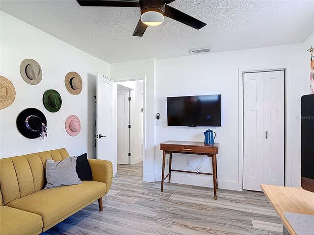 1421 Pine Tree Dr, Edgewater, FL 32132 - living area featuring a ceiling fan, light wood-style flooring, and a textured ceiling