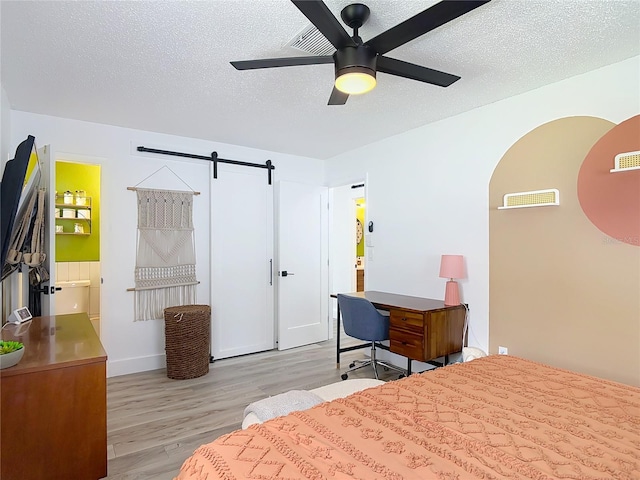 1421 Pine Tree Dr, Edgewater, FL 32132 - bedroom with wood finished floors, a textured ceiling, a barn door, and a ceiling fan